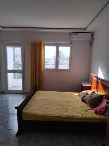 a bedroom with a bed and two windows at Appartement s 1 centre ville zarzis in Zarzis