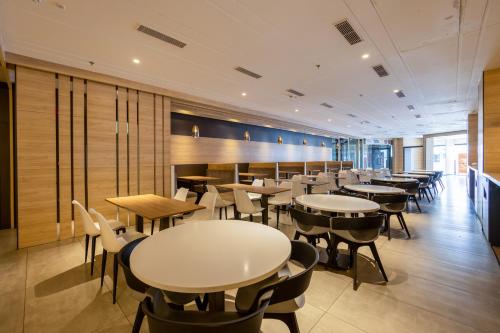 a restaurant with tables and chairs in a room at The Trot Hotel & Suites near Yashobhoomi Udyog vihar in Gurgaon