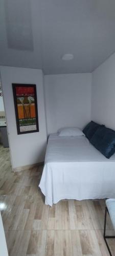 a bedroom with a white bed and a wooden floor at Hospedarte Cali Sur in Cali