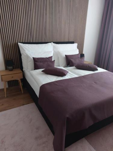 a large bed with purple and white pillows on it at Apartmán Astana in Levoča