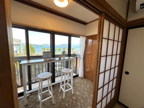 a room with a balcony with a laptop and two stools at Guest House HIIRAGI in Yamanakako