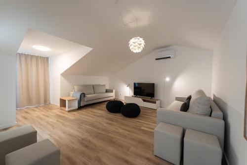 a living room with two white couches and a tv at Oceanside Village 2 in Lagoa