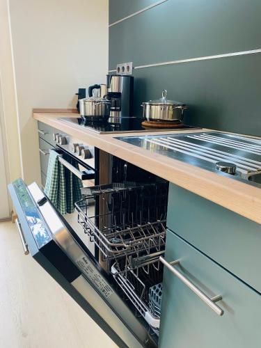 a kitchen with an open dishwasher with pots and pans at Apartments Aura & Nova in Aue-Bad Schlema