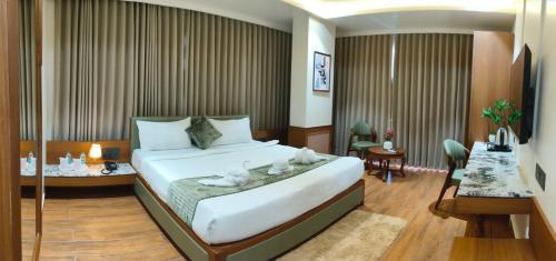 a hotel room with a bed and a dining room at Hotel Shlok Inn in Somnath