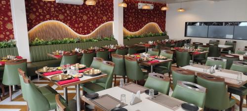 a dining room with tables and green chairs at Hotel Shlok Inn in Somnath