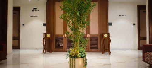a lobby with a palm tree in front of two elevators at Hotel Shlok Inn in Somnath