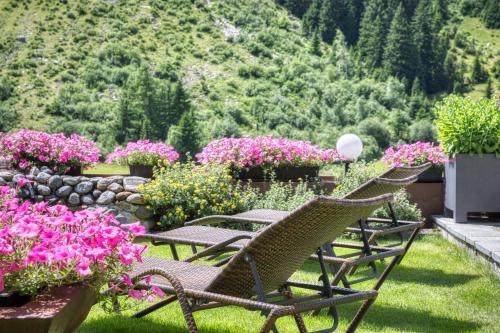 a row of chairs in a garden with flowers at GenussHotel Sonnblick in Sankt Leonhard im Pitztal