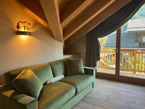 a green couch in a living room with a large window at Baita PierIta Stua Genziana e Ginepro in Bormio
