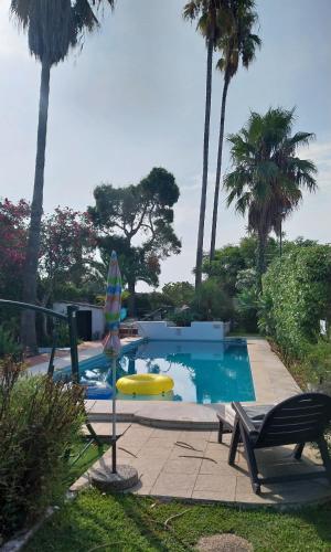 a swimming pool with an umbrella and a slide at Villa Casa das Palmeiras in Charneca