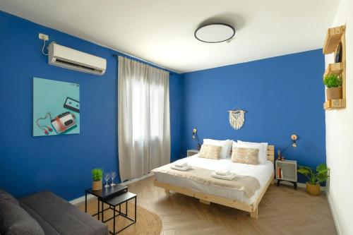 a blue bedroom with a bed and a couch at Rena's House - Beach Edition in Tel Aviv