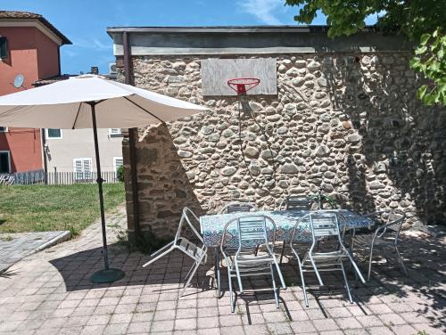 a table and chairs and an umbrella next to a stone wall at Casa Ottavina in Borgo a Buggiano
