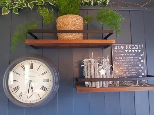 a clock on a wall next to a shelf at Merrywell Shepherds Hut in Offenham
