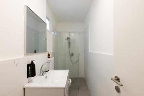 a white bathroom with a sink and a shower at Rena's House - Beach Edition in Tel Aviv