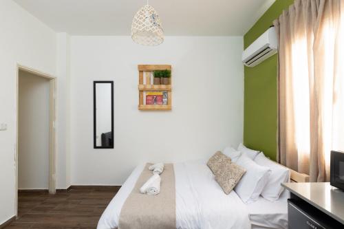 a bedroom with a white bed and a television at Rena's House - Beach Edition in Tel Aviv