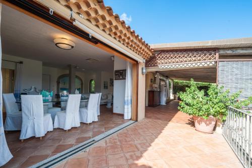 an outdoor patio with white chairs and a table at Villa Smeralda Punta Lada Porto Rotondo in Porto Rotondo