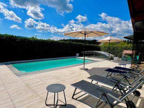 a swimming pool with two chairs and an umbrella at Modernes Ferienhaus mit Pool Nähe Wörthersee & Golfplatz in Feldkirchen in Kärnten