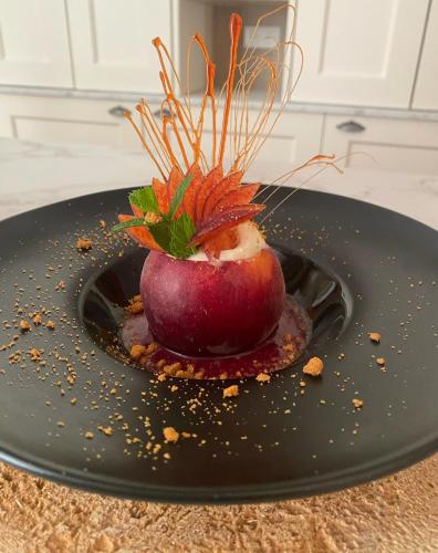 a red apple on a black plate on a counter at Logis Hôtels - Hôtel Restaurant Domaine Les Falaises in Martel