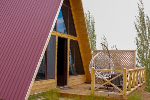 a house with a pink roof and a chair on a deck at IN CLOUDS RESORT Byurakan in Antarut
