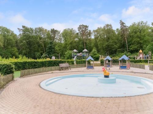 a small pool in a park with a playground at chalet in the woods with pool in Vledder