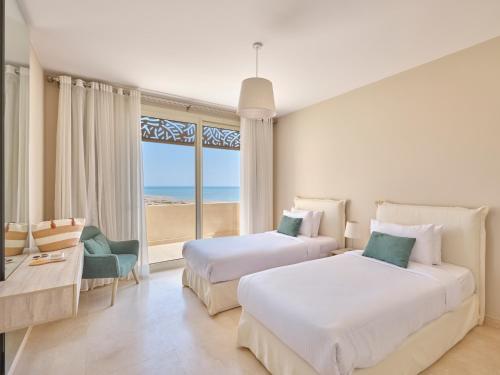 two beds in a room with a view of the beach at Boutique Residence Mangroovy-Lemon Spaces Gouna in Hurghada