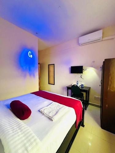 a bedroom with a bed with a red pillow and a desk at Queen Hotel in Morogoro