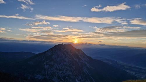 a mountain with the sun setting on top of it at Apartment Stoderzinken, gemütlich und ruhig in Gröbming
