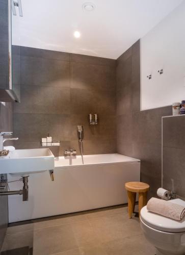 a bathroom with a tub and a sink and a toilet at Swiss Family Chalet in Andermatt