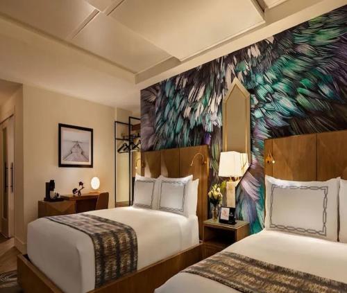 two beds in a hotel room with a peacock mural at Hotel Milano Near Delhi Airport in New Delhi