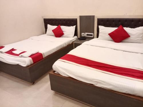 two beds in a room with red and white pillows at Royal SeaView in Digha