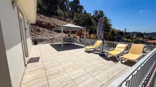 a patio with two chairs and an umbrella on a house at Cerca do casal in Santo Tirso
