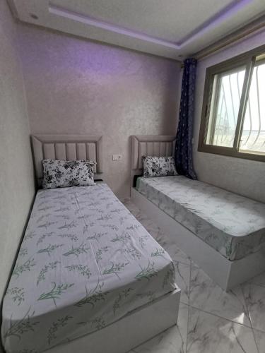 a bedroom with two beds and a window at Appartement rif roayal in Al Hoceïma