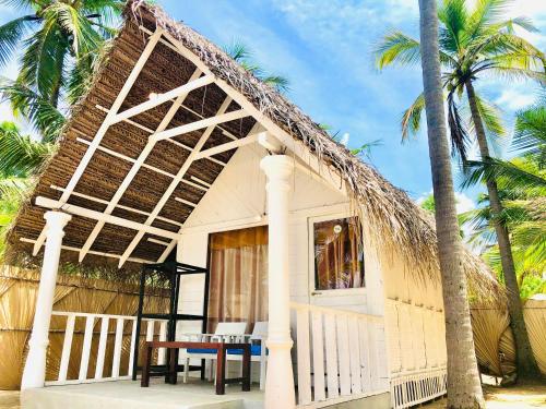 a small cottage with a thatched roof on a beach at Golden Beach Cottages in Trincomalee