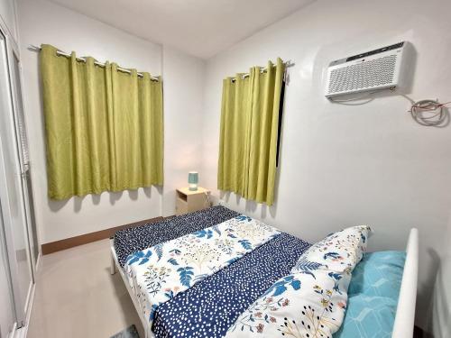 a bedroom with a bed and a fan and green curtains at Casa Alegre Lipa in Lipa