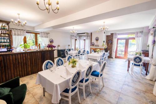 a dining room with white tables and blue chairs at Domki modułowe przy plaży in Sokole-Kuźnica