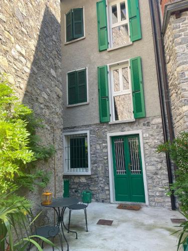 a building with green shutters and a table in front of it at PRIMA DEL CIELO - appartamento LAGO in Esino Lario