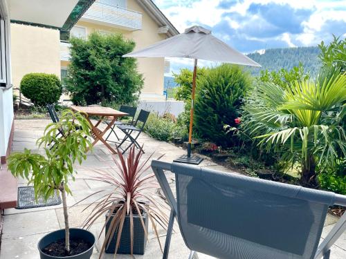 a patio with a table and an umbrella and plants at wanderlutz in Baiersbronn