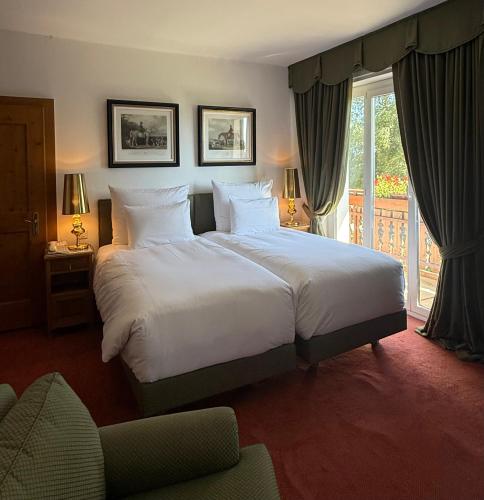 a bedroom with a large white bed and a balcony at Grand Hôtel du Golf & Palace in Crans-Montana