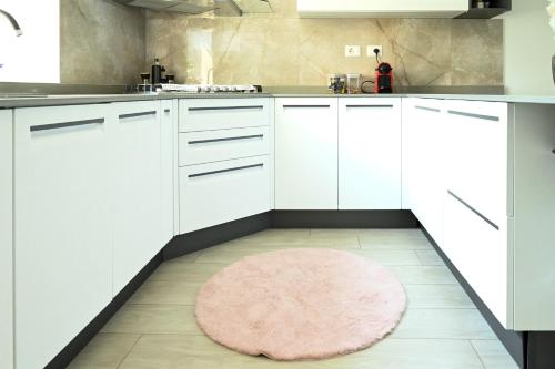 a kitchen with white cabinets and a pink rug on the floor at CASA Vacanze EUREKA in Novi Ligure
