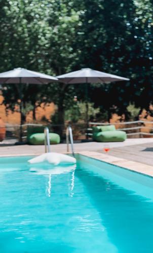 a swimming pool with twootation devices and umbrellas at EquiNatura - Silver Coast in Caldas da Rainha