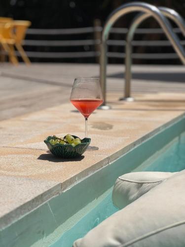 a glass of wine and a bowl of olives next to a pool at EquiNatura - Silver Coast in Caldas da Rainha
