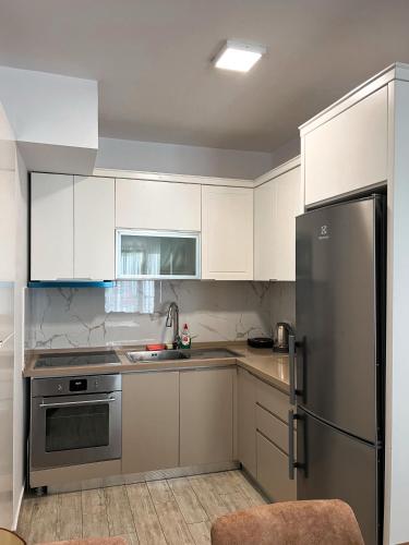 ティラナにあるRoes Appartment 4の白いキャビネットとステンレス製の冷蔵庫を備えたキッチン