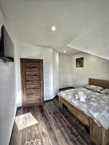a bedroom with a large bed and a wooden door at Apartmány Alexander in Vrbov