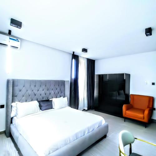 a bedroom with a white bed and an orange chair at Ifemide Estates - Luxury Homes in Akure