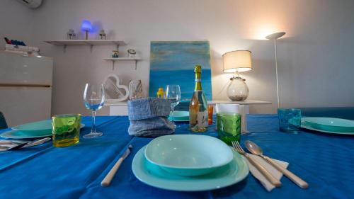 a blue table with plates and glasses and a bottle of wine at Galatea Executive Sea View in Aci Castello