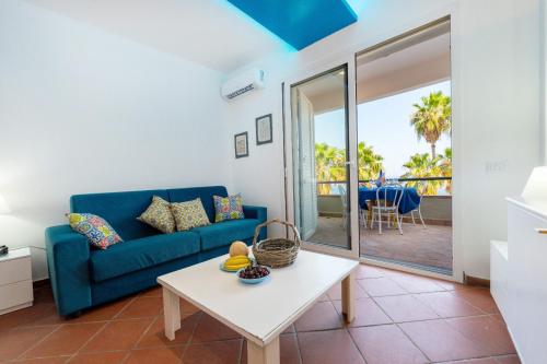 a living room with a blue couch and a table at Galatea Executive Sea View in Aci Castello