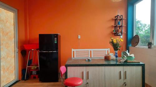 a kitchen with a black refrigerator and an orange wall at NEST HOUSE - Villa in Ấp Kim Thạch