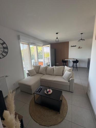 a living room with a white couch and a table at Moderne et Spacieux avec Vue dégagée in Bourgoin