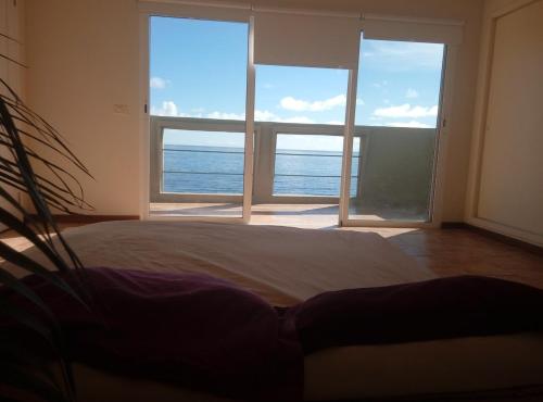 a bedroom with a view of the ocean through windows at Ático encima del mar in Santa Cruz de la Palma
