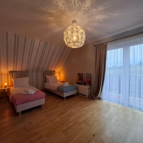 a living room with two beds and a chandelier at Apartamenty TUTERRA III in Zabagnie