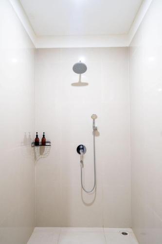 a white bathroom with a shower with a glass door at Kusuma Coliving & Villas in Canggu